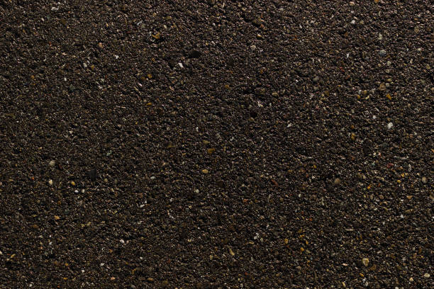 istock Black asphalt with various colored stones background texture 1198462774