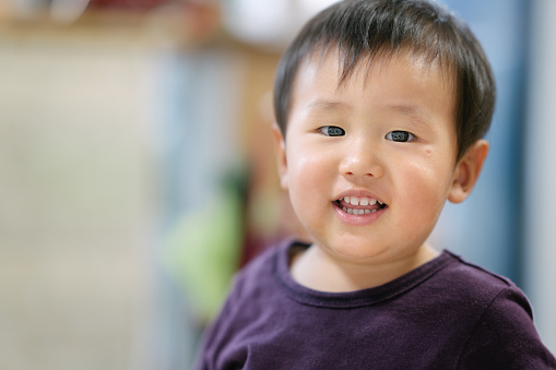 A portrait of a cute baby boy at home while looking at camera.