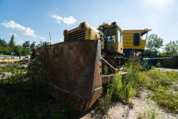 istock Old yellow rusty tractor in field in sunny day. 1198469402
