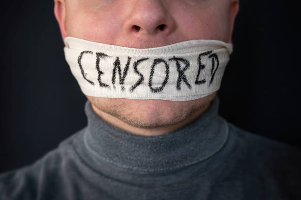 istock Man silenced by censorship with bandage over his mouth 1198469440