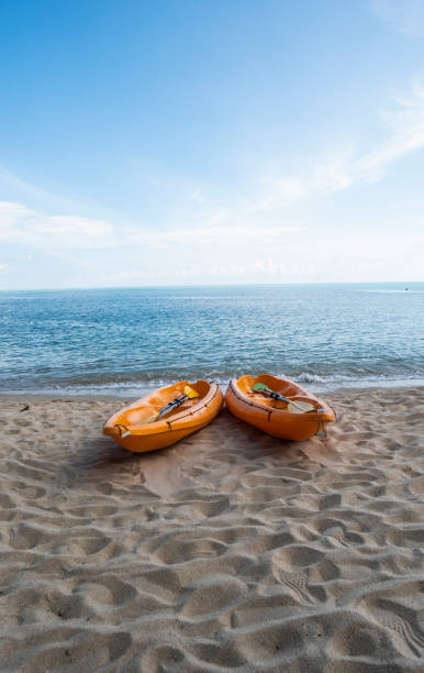 dwa kolorowe pomarańczowe kajaki na piaszczystej plaży gotowe dla wioślarzy w słoneczny dzień. kilka pomarańczowych łodzi rekreacyjnych na piasku. aktywna turystyka i rekreacja wodna. - blue kayak zdjęcia i obrazy z banku zdjęć