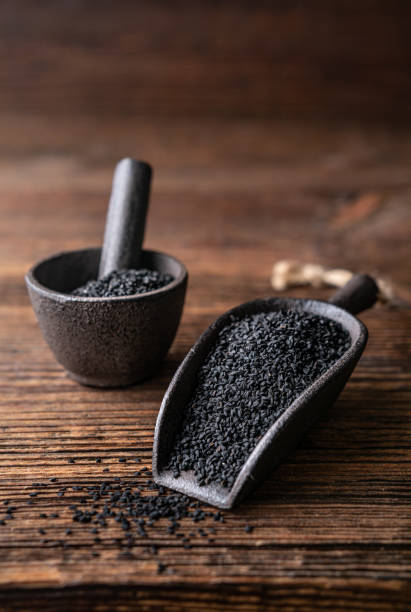 Nigella sativa seeds also known as black cumin, kalo jeera, kalonji and black caraway in iron scoop and mortar stock photo