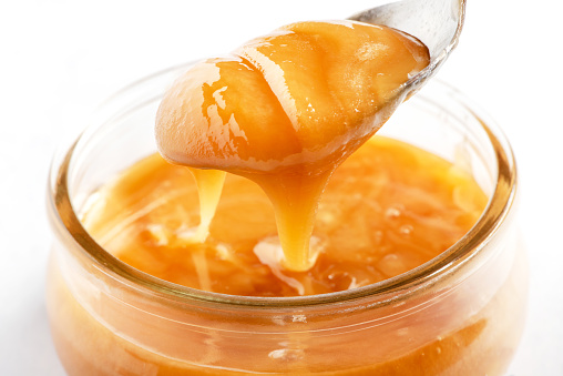 Crystallized thick honey flowing with a spoon close-up.