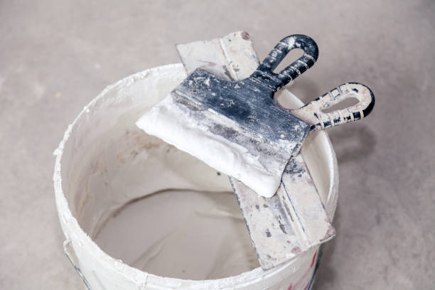 istock Decorative cement plaster and trowel in construction bucket ready for plastering. Spatula and bucket of white putty. Top view 1198476042