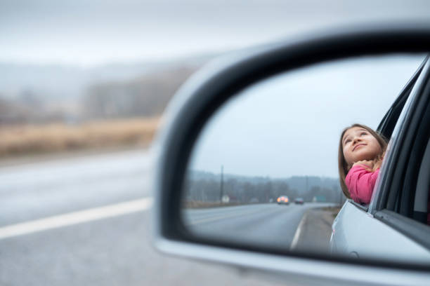 istock Young girl ride car and look out open window 1198486061