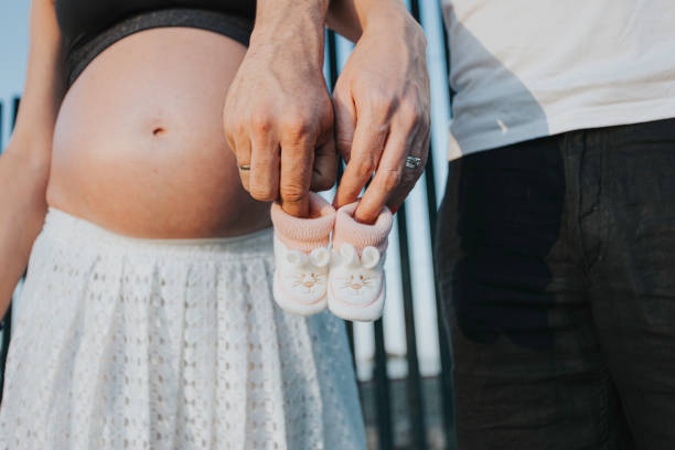 expecting parents holding little baby boy shoes - pair couple mid adult happiness imagens e fotografias de stock