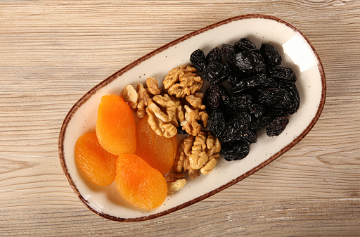 Dried apricots walnuts and dried black grapes on the same plate for the breakfast