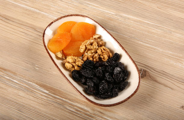 istock Dried apricots walnuts and dried black grapes on the same plate 1198489668