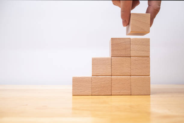 istock hand arranging wood cube stacking as stair step shape, mock up for create symbol or logo, business growth and management concept 1198490055
