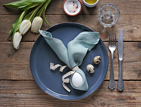 Easter festive table setting.  Elegant table decoration with fresh flowers and quail eggs. Flat layot