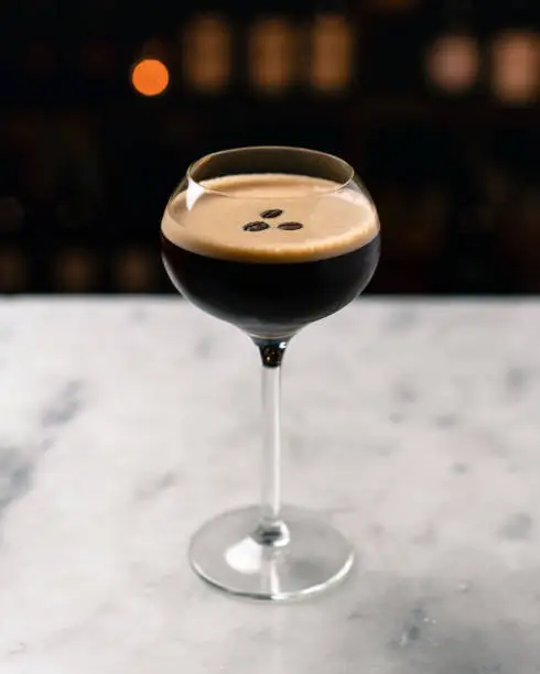 A coffee drink, espresso martini in a coupe glass on a marble table