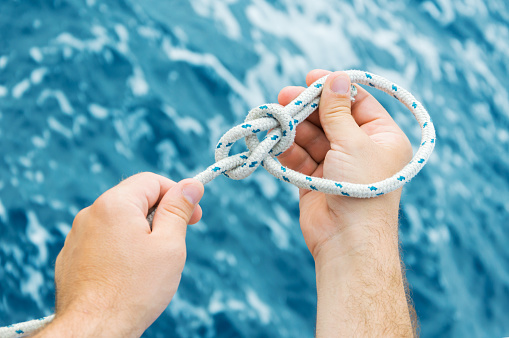 Closeup of the male hands making a bowline nautical knot