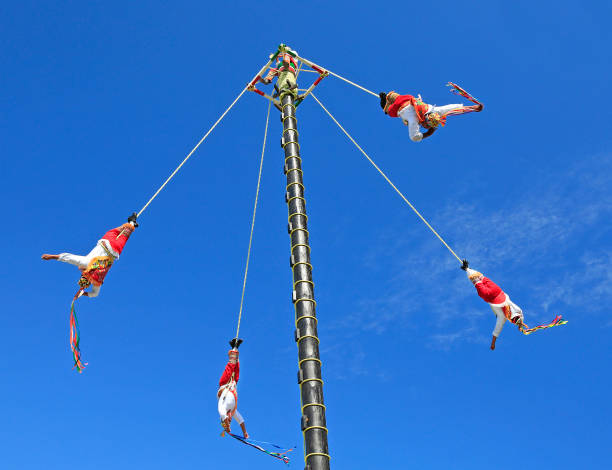 Flyers, or flyers performance, Mexico Riviera Maya, Mexico - December 27, 2019:The Voladores, or flyers performance. They climb up a very high pole their waist to ropes wound around the pole and then jump off, flying gracefully around it. volador stock pictures, royalty-free photos & images