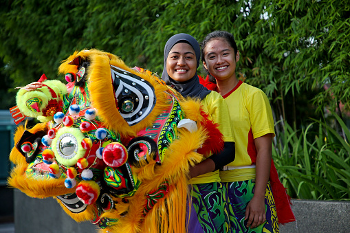 Two Muslim teenage girls actively performing Lion Dance for Chinese New Year celebration in Kuala Lumpur, Malaysia.