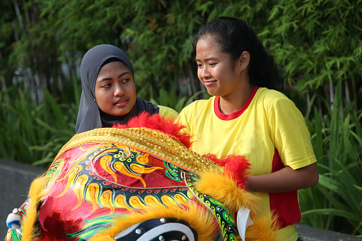 Indonesian ethnicity Muslim teenage girl is assisting her Malaysian friend gearing ready Lion Dance performance for Chinese New Year celebration in Kuala Lumpur, Malaysia.