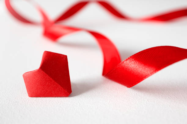 coeur d'origami et bandes de satin sur le fond blanc dans la vue avant. photo créative pour la saint-valentin ou invitation de mariage. concept beau amour - valentines day origami romance love photos et images de collection