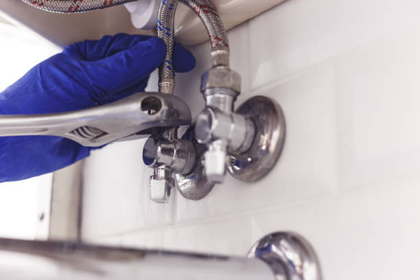 istock Plumber turns nut on angle valve under wash basin using spreading wrench. 1198498274