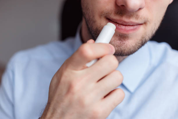 uomo che applica rossetto igienico sulle labbra per ravvivare le labbra screpolate ed evitare il primo piano asciutto - lip balm immagine foto e immagini stock