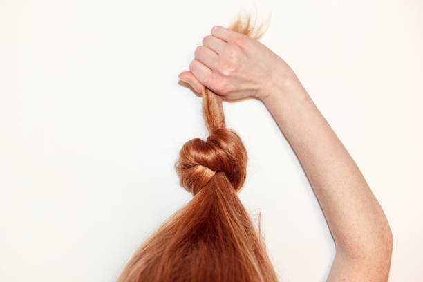 Red-haired girl pulls herself up in a knotted hair. Flat lay, isolated on white