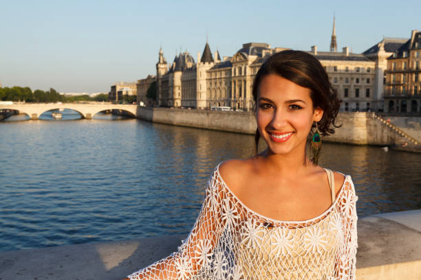 Beautiful young woman enjoying the sights of Paris by the River Seine at sunset.