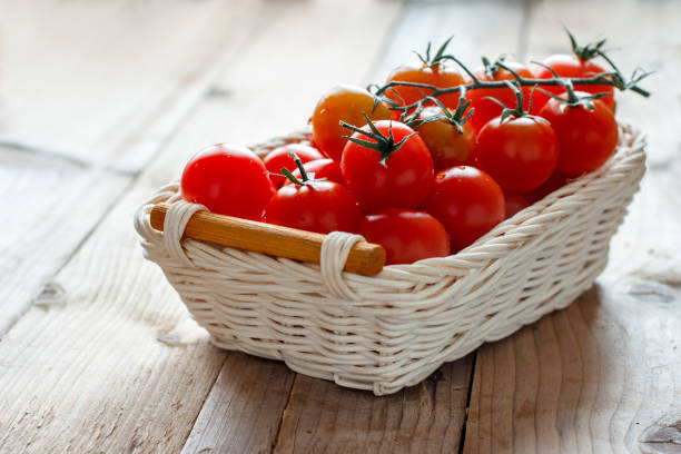 istock Fresh cherry tomatoes in Wicker basket on wooden table. 1198501461