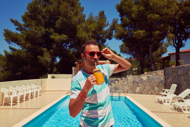 istock Attractive man drinking juice on the swimming pool. Summer concept. 1198502735