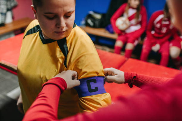Adjusting Captain Arm Band Female soccer player adjusting "captain" arm band to her teammate. soccer team captain stock pictures, royalty-free photos & images