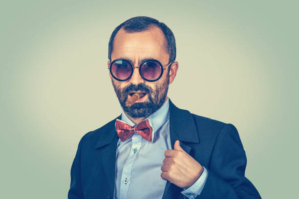 istock confident, rich, bearded man with sunglasses, looking camera and smoking cuban cigar isolated on light green yellow background 1198518353