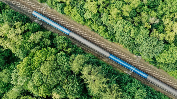 Aerial view of a train driving through a forest. Double track, near Prague, Czech Republic. Diagonal composition of a fast train driving on a double railroad track amongst trees. rail transportation stock pictures, royalty-free photos & images