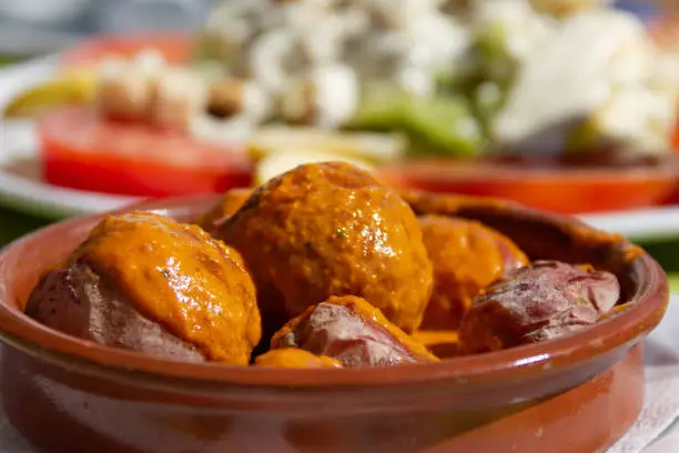 Photo of Delicious papas arrugadas with spicy mojo sauce on clay plate