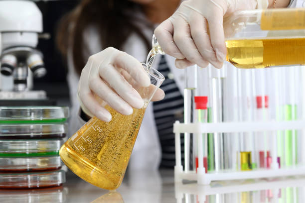 Female hand in white protective gloves pours beer Female hand in white protective gloves pours beer from bottle in test tube closeup. Food test concept food additive stock pictures, royalty-free photos & images