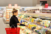 Woman shopping in supermarket reading product information.