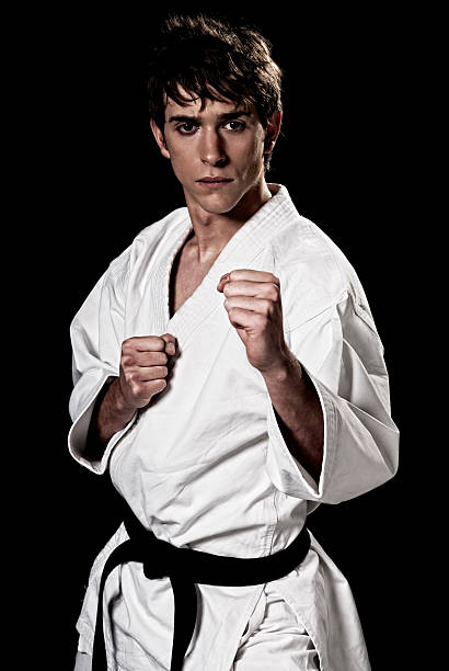 Karate male fighter young high contrast on black background. stock photo