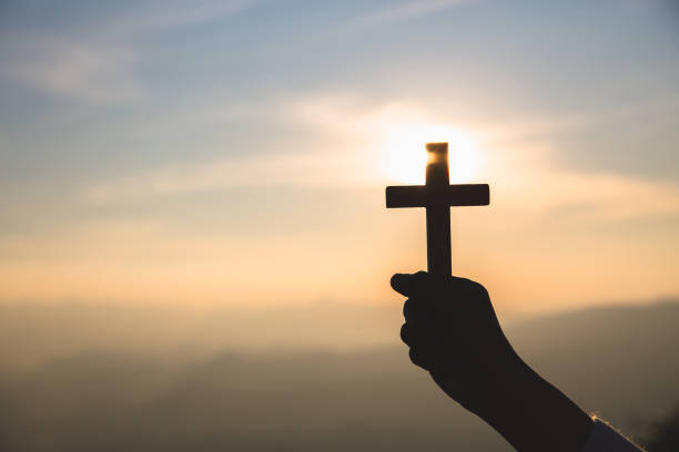 силуэт от рук, держащих деревянный крест на фоне восхода солнца, распятие, символ веры. - easter praying cross cross shape стоковые фото и изображения
