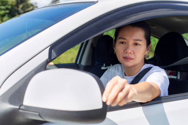 istock Asian woman behind steering wheel adjusting car side mirror 1198539418