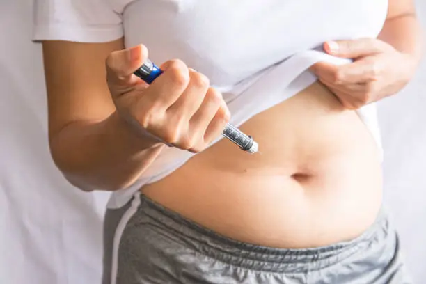 Diabetes concept insulin syringe injection shot into abdomen