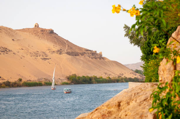 View from Elephantine Island of the Nile River and sand-covered hills on the river's west bank in Aswan, Egypt.