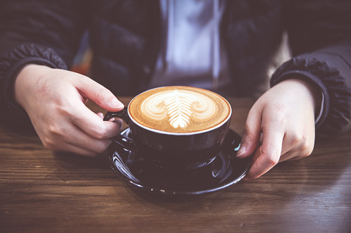 Woman hand holding a blue cup of hot coffee