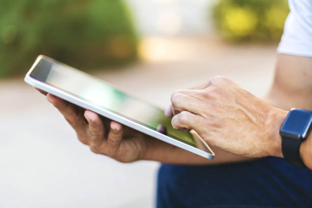 istock Hands of Millennial Male Using Digital Tablet Technology Outdoors 1198549302