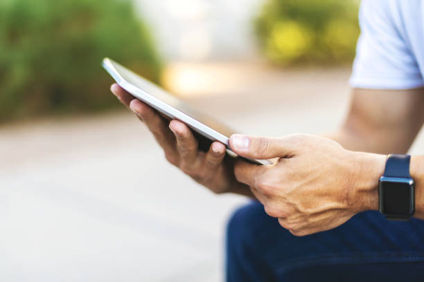 istock Hands of Millennial Male Using Digital Tablet Technology Outdoors 1198550057