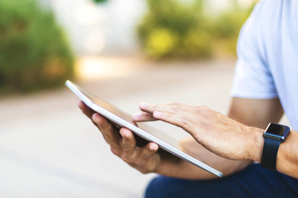 istock Hands of Millennial Male Using Digital Tablet Technology Outdoors 1198550147