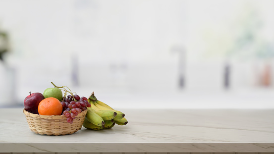Cropped shot of fruit basket and copy space on marble desk with blurred kitchen room background