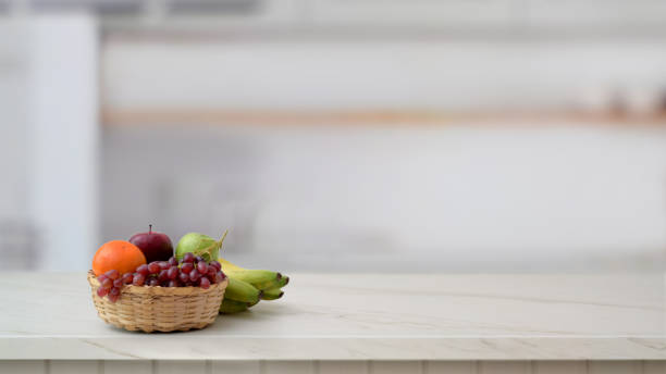 istock Close up view of fruit basket and copy space on marble desk with blurred kitchen room 1198552484