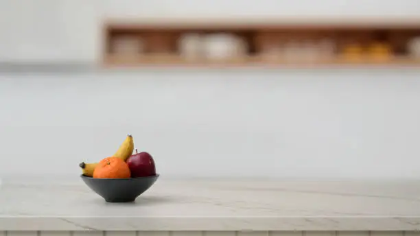 Photo of Cropped shot of fruit bowl and copy space on marble desk with blurred kitchen room