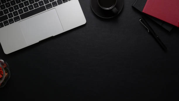 istock Top view of dark  workplace with laptop computer, office supplies and copy space on black table 1198552557