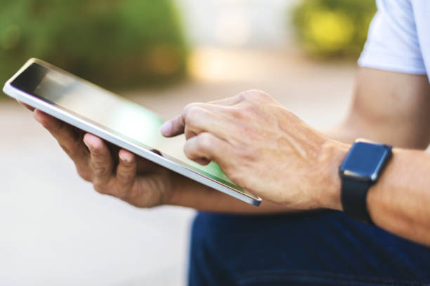 istock Hands of Millennial Male Using Digital Tablet Technology Outdoors 1198553362