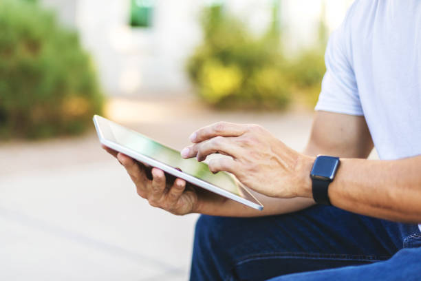 istock Hands of Millennial Male Using Digital Tablet Technology Outdoors 1198554027