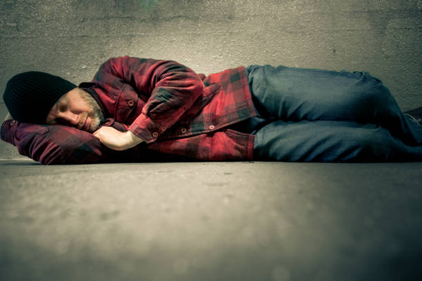 istock Homeless young man lying down in cold subway tunnel 1198556369