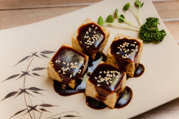 tofu no dengaku es tofu a la parrilla con semillas de sésamo y salsa hatcho miso sobre plato marrón y fondo de madera. - japanese cuisine soy sauce food bonito fotografías e imágenes de stock