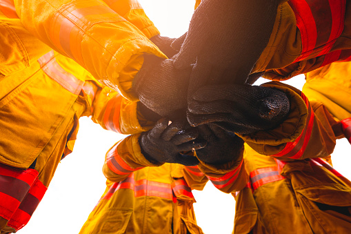 Firefighter putting hands up for fire fighting, Cheerful people giving strength motivation. Teamwork concept